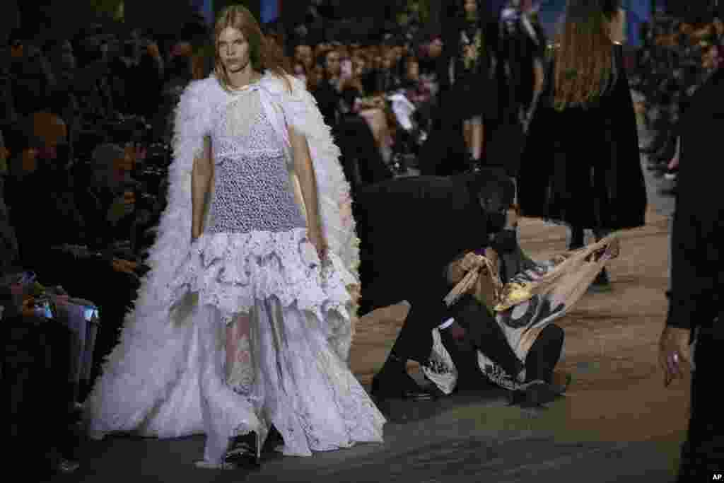 A protester is removed from the runway during the Louis Vuitton Spring-Summer 2022 ready-to-wear fashion show presented in Paris, France, Oct. 5, 2021.