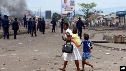 ARCHIVES - Une mère et ses enfants passent près de la police anti-émeute lors d'une manifestation à Kinshasa, en République démocratique du Congo, lundi 19 septembre 2016.