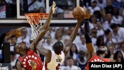 Luol Deng N.9 de Miami Heat mène une attaque sous le panneau face à Bismack Biyombo N.8 et DeMarre Carroll N.5 des Raptors de Toronto qui défendent pour leur équipe lors du match 6 des demi-finales de la Conférence Est de la NBA de basket-ball, 13 mai 2016, à Miami.