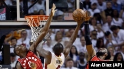 Luol Deng du Miami Heat (9) contre Bismack Biyombo des Toronto Raptors (8) et DeMarre Carroll (5) , le 13 mai 2016 à Miami. 