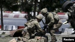 FILE - U.S. soldiers attend to a wounded soldier at the site of a blast in Kabul, Afghanistan, June 30, 2015. 