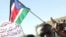 A Sudanese opposition supporter shouts slogans as protesters wave the flag of Sudan People's Liberation Movement (SPLM) during a demonstration against the government in Khartoum, 07 Dec 2009
