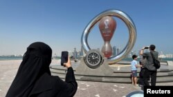 A woman takes a photograph of the FIFA World Cup Qatar 2022 countdown clock in Doha, Qatar, Oct. 17, 2022.