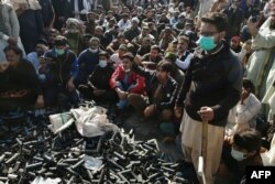Activists and supporters of Tehreek-e-Labbaik Pakistan (TLP) gather beside empty tear gas shells fired by police during an anti-France demonstration in Islamabad, Nov. 16, 2020.