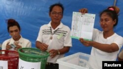 FILE - An electoral member shows a ballot during the vote counting, during the general election in Bangkok, Thailand, March 24, 2019. 