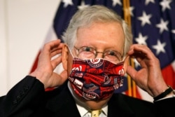 FILE - Senate Majority Leader Mitch McConnell of Kentucky puts on a face mask on Capitol Hill in Washington, July 21, 2020, .