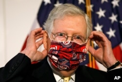 FILE - Senate Majority Leader Mitch McConnell of Kentucky puts on a face mask on Capitol Hill in Washington, July 21, 2020, .