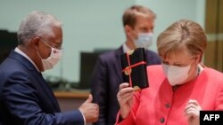 António Costa (e), primeiro-ministro de Portugal, oferece um presente a chanceler alemã, Angela Merkel( d), num dos intervalos da cimeira de Bruxelas. 