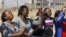 Women from a group of churchgoers wail at the site, Sunday Aug. 19, 2012 at the Lonmin platinum mine, background, near Rustenburg, South Africa, during a memorial service for 34 dead striking miners who were shot and killed by police last Thursday.