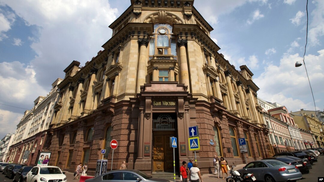People in downtown Moscow walk past the headquarters of the Bank of Moscow, one of several banks subject to new EU sanctions, Russia, July 30, 2014.