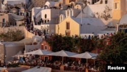 FILE - Tourists wait to view Santorini’s famed sunset, on Santorini, Greece, July 25, 2024. 