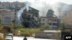 People drive next to a building, targeted in an Israeli airstrike the night before, in Beirut's southern suburbs on Oct. 20, 2024.