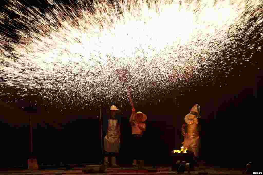 Folk artists create sparks with molten iron during a performance in Hengnan county, Hunan province, China, July 17, 2019.