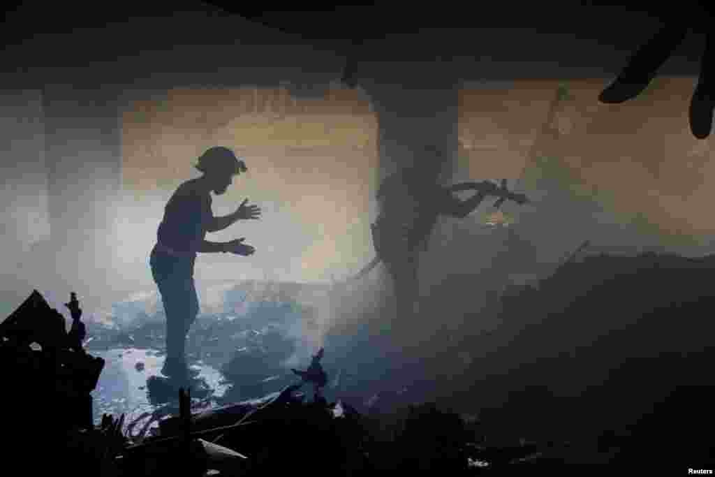 Palestinians work to extinguish fire at a school sheltering displaced people, after it was hit by an Israeli strike, in Gaza City.