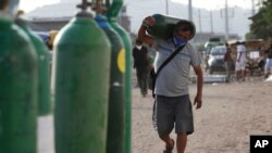 A man carries his empty oxygen tank to be filled in the Villa El Salvador neighborhood, in Lima, Peru, April 11, 2021, during the general elections amid the new coronavirus pandemic. 