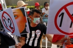 A demonstrator holds signs during a pro-democracy rally demanding changes in the monarchy and government in Bangkok, Thailand, Dec. 10, 2020.