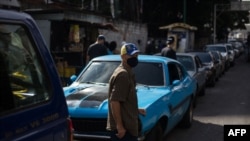 Un hombre espera junto a su vehículo en una larga línea para abastecerse de gasolina en una estación de servicio en Caracas, Venezuela, el 5 de octubre de 2020.