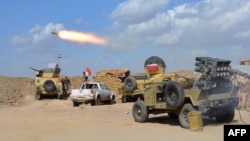 FILE - Iraqi government forces and allied militias fire weaponry from a position in the northern part of Diyala province as they conduct an assault to retake the city of Tikrit from the Islamic State group March 2, 2015. On Monday they launched a similiar assault on Fallujah.