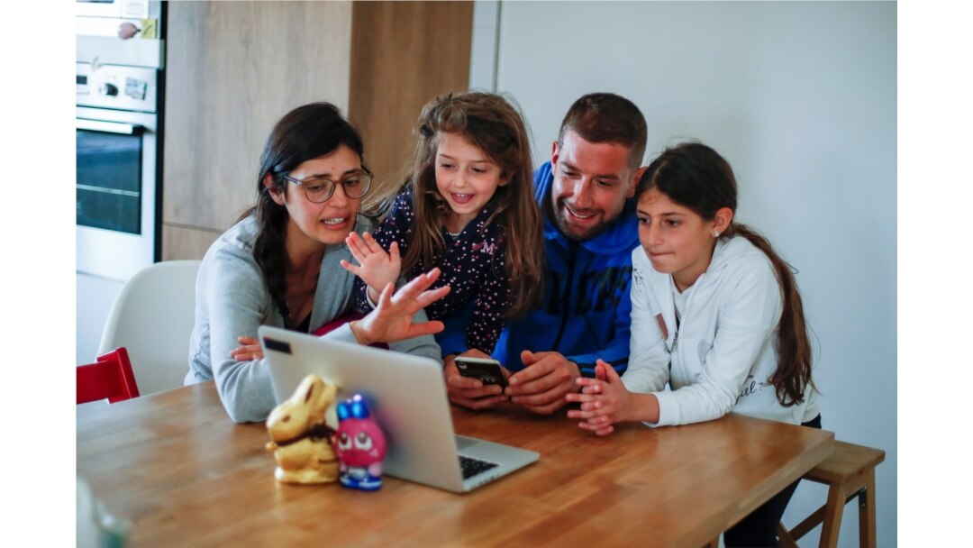 La familia Perrini usa un teléfono móvil y una computadora portátil para hacer una videollamada para estar en contacto con sus familiares durante un encierro.