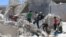 People walk on the rubble of a site hit by a barrel bomb in the rebel-held area of Old Aleppo, Syria, July 11, 2016. 