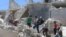 People walk on the rubble of a site hit by a barrel bomb in the rebel held area of Old Aleppo, Syria July 11, 2016. 