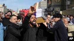 Mourners carry a coffin of prominent social activist Wissam al-Ghrawi in Basra, Iraq, Nov. 18, 2018. 