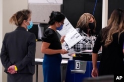 FILE - The Maricopa County Elections Department officials conduct a post-election logic and accuracy test for the general election as observers watch the test, November 18, 2020, in Phoenix, Arizona.