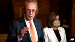 FILE - Sen. Chuck Schumer, D-N.Y., speaks to reporters as House Speaker Nancy Pelosi, D-Calif., listens on Capitol Hill in Washington, Aug. 6, 2020.