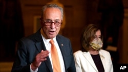 FILE - Sen. Chuck Schumer, D-N.Y., speaks to reporters as House Speaker Nancy Pelosi, D-Calif., listens on Capitol Hill in Washington, Aug. 6, 2020.