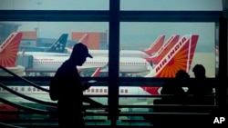 FILE - A man is silhouetted against an airport window with Air India planes parked in the background in New Delhi, Oct. 31, 2023.