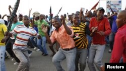 Striking miners dance and cheer after they were informed of a 22 percent wage increase offer outside Lonmin's Marikana mine, 100 km (60 miles) northwest of Johannesburg, September 18, 2012. 