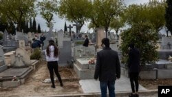 Relatives wearing face masks to protect against coronavirus observe social distancing guidelines during a burial at a Madrid cemetery during the coronavirus outbreak in Madrid, Spain, March 27, 2020.