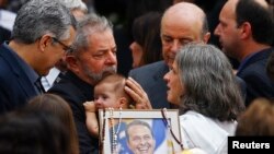 Mantan Presiden Brazil, Luiz Inacio Lula da Silva menggendong anak bayi mendiang Eduardo Campos dalam upacara pemakaman Campos di Recife (17/8).