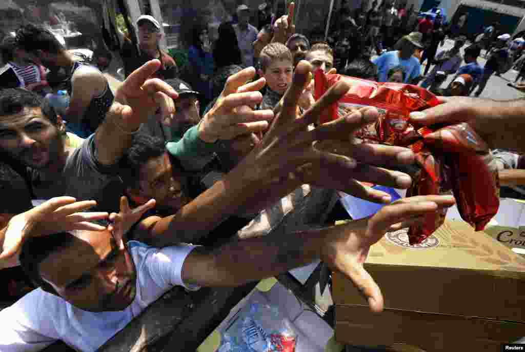 Syrian refugees and other migrants struggle to get dry food during aid distribution by municipality workers on the Greek island of Kos, Aug. 14, 2015. 