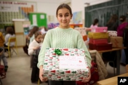 Merjem, 10, poses for a photo with one of the presents prepared for Ukrainian children at Safvet Beg Basagic elementary school in Sarajevo, Bosnia, Tuesday, Dec. 20, 2022. (AP Photo/Armin Durgut)