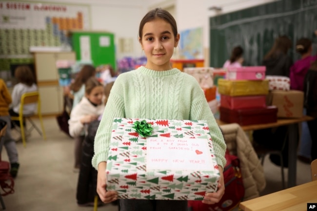 Merjem, 10, poses for a photo with one of the presents prepared for Ukrainian children at Safvet Beg Basagic elementary school in Sarajevo, Bosnia, Tuesday, Dec. 20, 2022. (AP Photo/Armin Durgut)