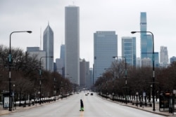 A person walks across the usually busy Columbus Drive that splits Chicago's Grant Park, on the first work day since Illinois Gov. J.B. Pritzker gave a shelter in place order, March 23, 2020.