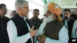 Menteri Pertahanan Pakistan Khawaja Muhammad Asif, kiri, berbicara dengan pemimpin partai Jamat Ulema-e-Islam Maulana Fazalur Rehman di luar parlemen di Islamabad (10/4).