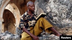 Un Tanzanien récite des versets du Coran assis parmi les ruines d'une ancienne mosquée sur l'île de Kilwa Kisiwani, Tanzanie le 30 octobre 2006.