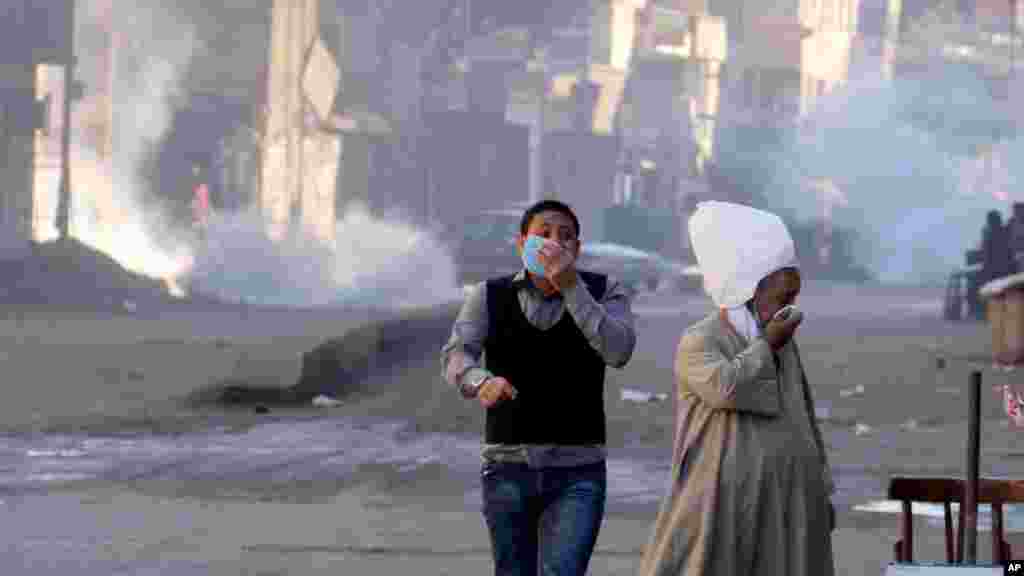 Egyptians react to tear gas fired by security forces to disperse a protest by supporters of ousted President Mohammed Morsi, Cairo, Dec. 6, 2013. 