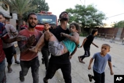 FILE— Palestinians carry a wounded girl after being rescued from under the rubble of buildings that were destroyed by Israeli airstrikes in Jabaliya refugee camp, northern Gaza Strip, November 1, 2023.