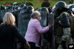 A woman argues with riot police during an opposition rally to protest the presidential inauguration of Alexander Lukashenko, in Minsk, Belarus, Sept. 23, 2020.