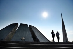 FILE - Two people walk at the Tzitzernakaberd memorial to the victims of mass killings by Ottoman Turks, in the Armenian capital, Yerevan, Oct. 30, 2019.