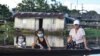 Una mujer y dos niñas usando mascarillas para protegerse del coronavirus se desplazan en un bote por el río Amazonas en Leticia, Colombia, el 13 de mayo de 2020.