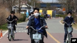 8일 한국 서울의 공원에서 신종 코로나바이러스 감염증(COVID-19)를 피하기 위해 마스크를 착용한 중학생들이 자전거를 타고 있다. 