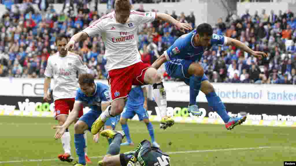 Hamburger SV's Slobodan Rajkovic (L) and Hoffenheim's Kevin Volland (R) jump over Hamburger SV's goalkeeper Rene Adler as he saves the ball during their German first division Bundesliga soccer match in Sinsheim May 11, 2013.