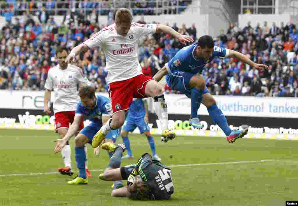 Slobodan Rajkovic (esq) do Hamburger SV e Kevin Volland (dir) do Hoffenheim saltam sobre o guarda-redes Rene Adler do Hamburger em jogo do campeonato da primeira divis&atilde;o alem&atilde; (11 Maio 2013.