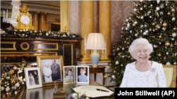 En esta fotografía difundida el lunes 25 de diciembre de 2017, la reina Isabel II posa sentada en un escritorio en la habitación 1844 del Palacio de Buckingham, en Londres, después de grabar su mensaje por el día de la Navidad que sería transmitido a la mancomunidad británica.