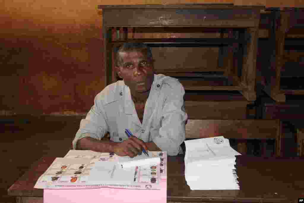 An election worker oversees the distribution of legislative election ballot papers at a polling station in Conakry, Guinea, Sept. 28, 2013.
