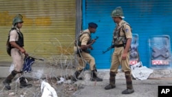 Indian paramilitary soldier cross barbed wire set up as road blockade at a temporary checkpoint during curfew in Srinagar, Indian controlled Kashmir, Monday, July 11, 2016.